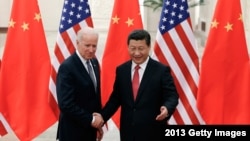 资料照片:中国国家主席习近平与时任美国副总统的拜登在北京人民大会堂握手合影。(2013年12月4日)