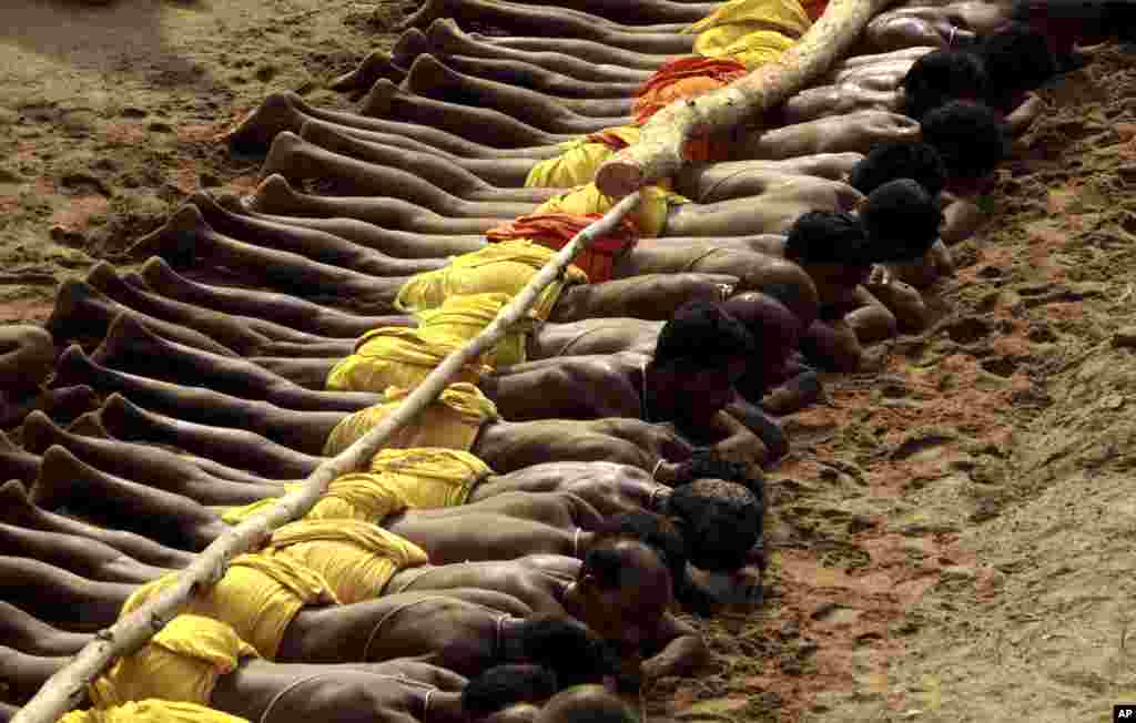 Beberapa warga Hindu melakukan ritual penebusan dosa dengan berbaring pada pasir yang panas, pada hari kedua festival Danda atau festival penghukuman diri untuk menenangkan Dewa Siwa, dewa kehancuran bagi umat Hindu, di Kulagarh, negara bagian Orissa, India timur.