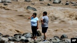 A couple looks at the overflowing Maipo River in San Alfonso, Santiago, Chile, Feb. 26, 2017. 