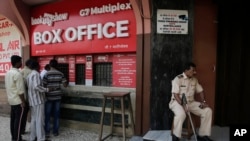 A policeman guards as people buy tickets at a movie theatre screening Bollywood film "Padmaavat" in Mumbai, India, Jan. 25, 2018. 