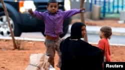 A homeless Syrian woman and her children are seen along a street in Beirut, July 22, 2013.