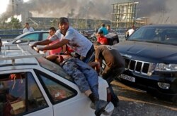 FILE - An injured man lies at the back of a car before being rushed away from the scene of a massive explosion at the port of Lebanon's capital Beirut, Aug. 4, 2020.