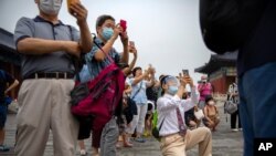 Parents wearing face masks to protect against the coronavirus take photos of students as they pose for a group photo at the Temple of Heaven in Beijing, July 18, 2020. 