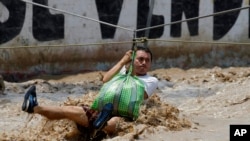 Un hombre es jalado en un arnés de tirolesa en Lima, Perú, el viernes 17 de marzo de 2017. El número de personas muertas en Perú luego de intensas lluvias y deslizamientos de tierra causando estragos alrededor de la nación andina trepó a 67 el viernes.