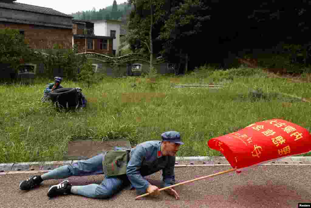 A man in "Red Army" garb hits the pavement during a simulated attack during a re-staging of part of the Long March in Jinggangshan.