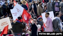 Des manifestants tunisiens brandissent le drapeau national devant le parlement à Tunis, le 14 novembre 2021.