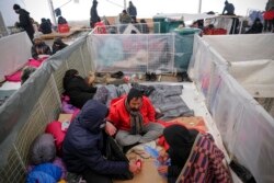 Migrants sit in a temporary shelter at the Lipa camp northwestern Bosnia, Dec. 26, 2020. Hundreds of migrants are stranded in a burned-out, squalid camp in Bosnia as heavy snow fell in the country and temperatures dropped.