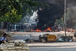 Security forces gather behind a burning barricade during a crackdown on protests against the military coup in Yangon on March 17, 2021. (Photo by STR / AFP)