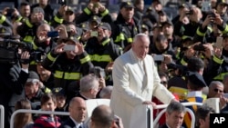 A boy and a girl sit behind Pope Francis in his pope-mobile as he tours St. Peter's Square at the Vatican before his weekly general audience, March 2, 2016.