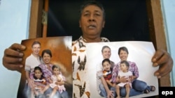 Indonesia -- Widi Yuliono a relative of John Paulisen, shows photographs of John Paulisen (Top-L), Yuli Hastini (Top-R), Arjuna Martin Paulisen (L) and Sri Paulisen (R) who are victims of the Malaysian Airline flight MH 17 plane downing in eastern Ukraine