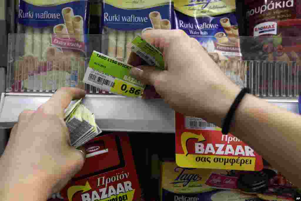 Many goods and services become more expensive on Monday as a result of a rise in Value Added Tax approved by Parliament last week. Pictured here, an employee of a supermarket replaces the prices with the new Value Added Tax (VAT) in Athens, July 20, 2015.