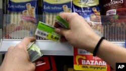 FILE: An employee of a supermarket replaces the prices with the new Value Added Tax (VAT) in Athens, Monday, July 20, 2015. 