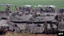 Israeli army troops stand around their tanks in an area along the border with the Gaza Strip in southern Israel on April 10, 2024, amid the ongoing conflict in the Palestinian territory between Israel and the militant group Hamas. (Photo by JACK GUEZ / AF