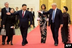 U.S. President Donald Trump, second right, gestures toward China's President Xi Jinping, third left, as U.S. first lady Melania Trump, center, and Xi's wife Peng Liyuan, right, look on at the Great Hall of the People in Beijing, Nov. 9, 2017.