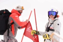 Kiana Kryeziu (kanan), bersama ayahnya, Visar Kryeziu, fotografer The Associated Press, memperbaiki bendera saat berlatih ski di pusat Ski Arxhena di Dragas, Kosovo, Sabtu, 22 Januari 2022. (AP)