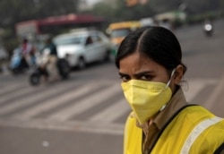 FILE - A policewoman wears a mask to protect herself from air pollution on a smoggy morning in New Delhi, Nov. 4, 2019.