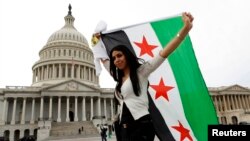 یک شهروند سوری تبار مخالف اسد، پرچم موسوم به «پرچم آزادی سوریه» را نزدیک کنگره آمریکا برافراشته است. واشنگتن، عکس از آرشیو