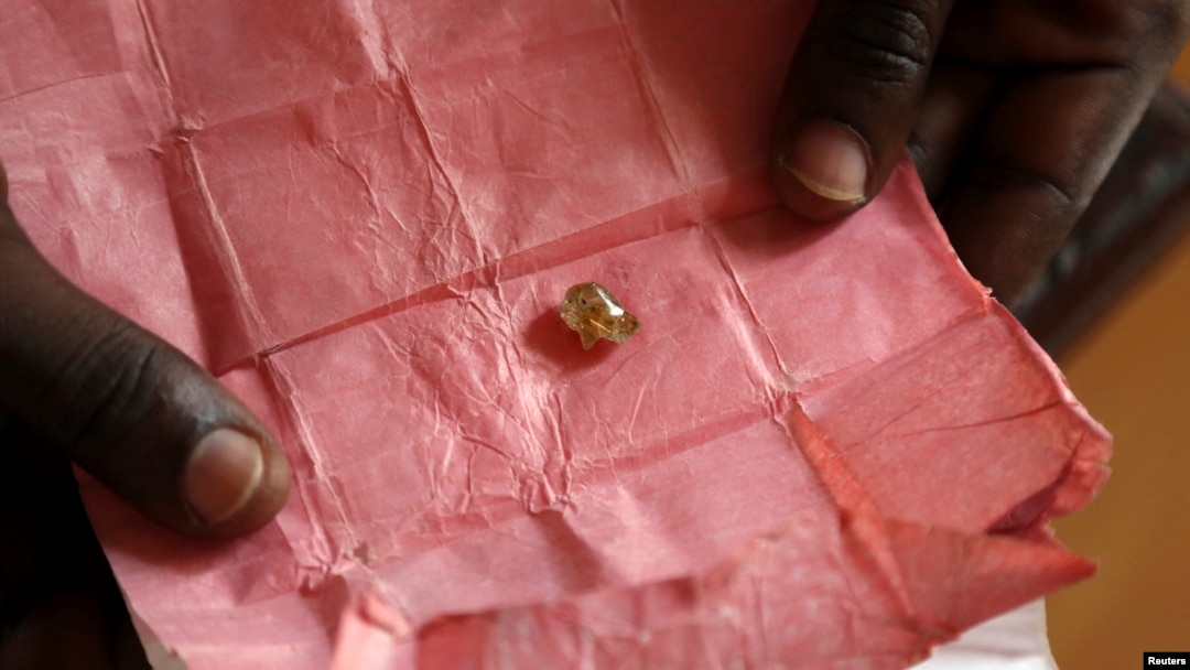 FILE - A man displays a rough diamond from the Boda region, for sale in Bangui, Central Africa Republic, May 1, 2014.