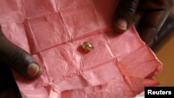 FILE - A man displays a rough diamond from the Boda region, for sale in Bangui, Central Africa Republic, May 1, 2014. 