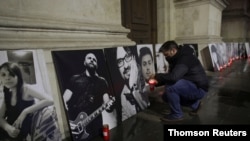 Activist Marian Raduna lights a candle in front a portrait of one of the victims of the Colectiv fire during an event that commemorates the blaze's 65 victims in Bucharest, Romania, Oct. 30, 2020. 