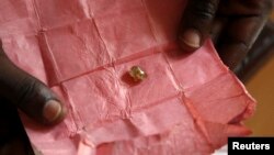 FILE - A man displays a rough diamond from the Boda region, for sale in Bangui, Central Africa Republic. Activists in Botswana slammed the Kimberley Process, which is intended to prevent diamonds from financing wars, after meetings this week failed to censure Russia.