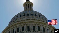 FILE - The U.S. flag flies next to the Capitol in Washington, July 14, 2011.