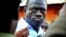 FILE - Ugandan opposition leader Kizza Besigye speaks to journalists, May 19, 2011, outside his house shortly after returning home after a confrontation with police, in Kasangati, Uganda. 