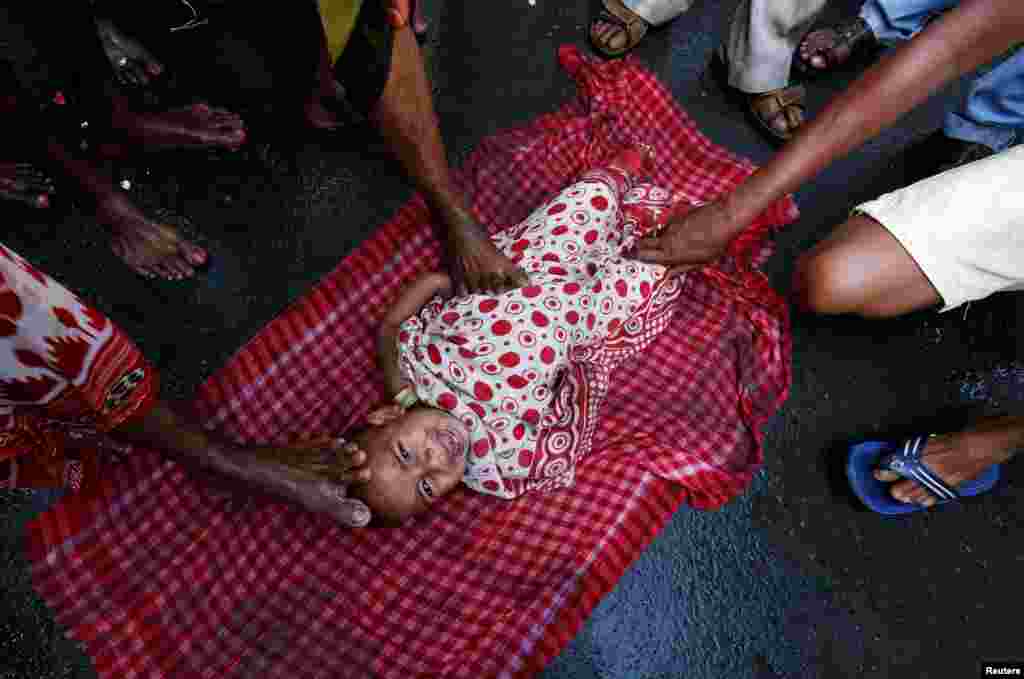 Orang-orang suci Hindu menyentuh seorang anak dengan kakinya, sebagai bagian dari &#39;ritual pemberkatan&#39; pada perayaan festival Gajan di Kolkata, India.