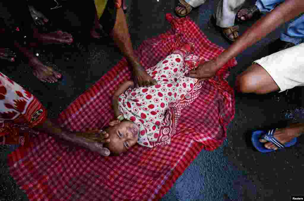 Hindu holy men touch a child with their feet as part of a ritual to bless him during a religious procession to mark the Gajan festival in Kolkata, India.