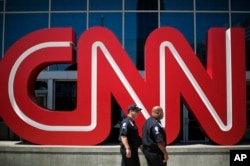 FILE - Security guards walk past the entrance to CNN headquarters in Atlanta.