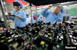 FILE - Employees work on a FiberHome Technologies Group factory production line in Wuhan, Hubei province, China, July 27, 2015. China relaxed its one-child policy Oct. 29, in part, to try to offset the country’s shrinking workforce.