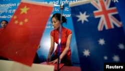 FILE - A stewardess arranges documents before a seminar of Australia China bilateral cooperation in resources and infrastructure in West Australia, in Beijing.