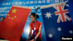 FILE - A stewardess arranges documents before a seminar of Australia-China bilateral cooperation in resources and infrastructure in West Australia, in Beijing, July 23, 2009. 