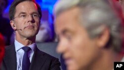 Dutch Prime Minister Mark Rutte, left, and PVV party leader Geert Wilders, right, wait to take their turn in the closing debate at parliament in The Hague, Netherlands, March 14, 2017.