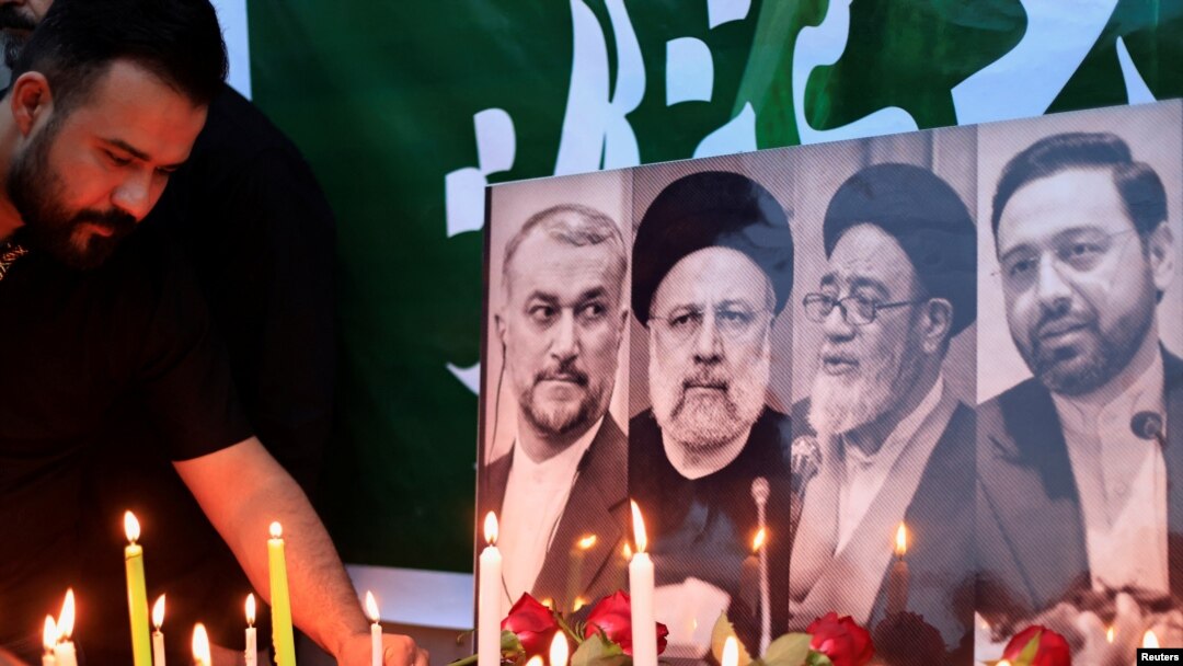 Seorang pria tampak menyalakan lilin di dekat foto mendiang Presiden Iran Ebrahim Raisi dan sejumlah tokoh lainnya di luar kedutaan besar Iran di Baghdad, Irak, pada 20 Mei 2024. (Foto: Reuters/Thaier Al-Sudani)
