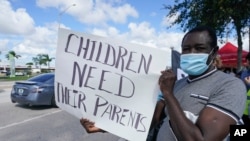 FILE - Temporary Protected Status holder Eddy Belt of Haiti holds up a sign as he demonstrates during a rally for a permanent solution for TPS holders in front of the Citizenship and Immigration Services field office, Oct. 17, 2020, in Miami. 