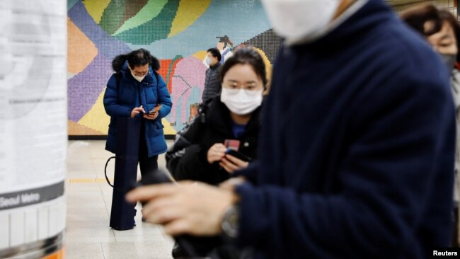 Park Gyung-sun checks his mobile phone before getting out of a subway station as he delivers a parcel in Seoul, South Korea, Feb. 8, 2023.