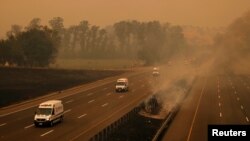 Una caravana de vehículos de emergencia circula por una carretera cerca del complejo de una compañía eléctrica afectada por los incendios en Vacaville, California, el 19 de agosto de 2020.