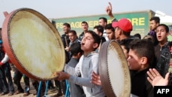 Displaced Iraqi people, who fled the violence in the Iraqi city of Ramadi, celebrate after their city was liberated from the Islamic State group, Dec. 29, 2015 at the Alkzenzanah camp in the capital, Baghdad.