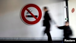 FILE - A woman and child walk past a "No Smoking" sign. A Yale-led study has found that nicotine exposure during pregnancy can trigger long-term genetic changes in unborn babies.