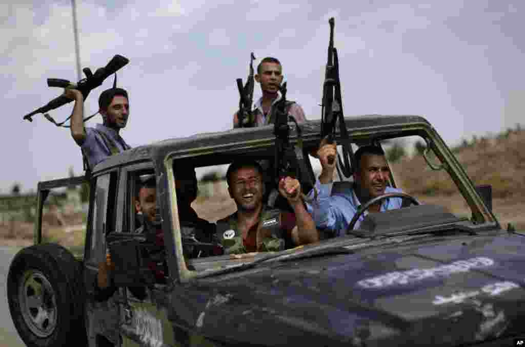 Syrian rebel fighters raise their weapons as they head to fight government forces in Aleppo, in Suran, on the outskirts of Aleppo, Syria, September 10, 2012. 