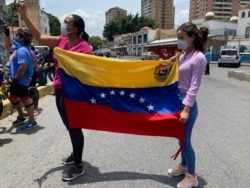 Feligreses con una bandera esperan en la calle el paso de la procesión.