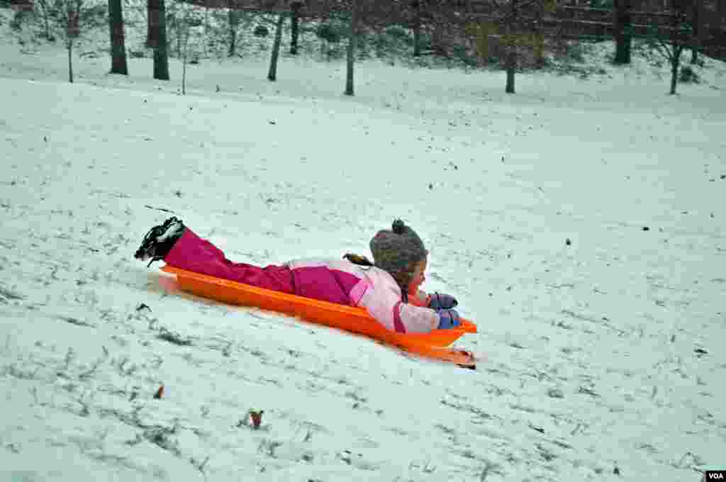 Seorang anak bermain seluncur di salju yang turun di Washington D.C.
