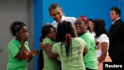 Jóvenes abrazan al presidente Obama durnate una visita a un colegio en Cleveland.