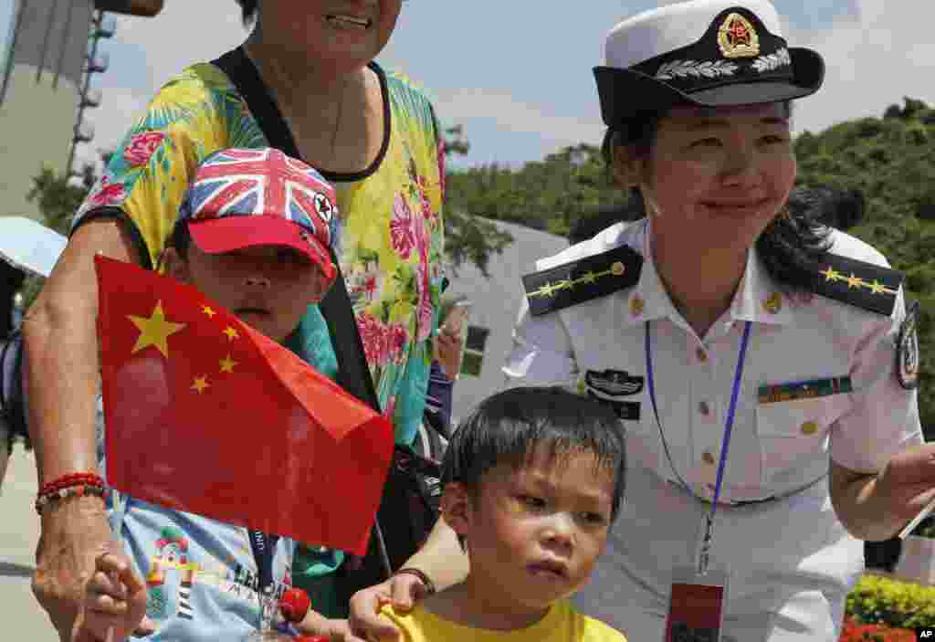 Para pengunjung berfoto bersama personel Tentara Pembebasan Rakyat (PLA) People&#39;s Liberation Army (PLA) dalam pembukaan Pangkalan Angkatan Laut Pulau Stonecutter di Hong Kong, yang menandai peringatan 18 tahun diserahkannya Hong Kong ke China (1/7). (AP/Kin Cheung)
