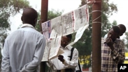 FILE - People read Congolese newspapers hung up by newspaper vendors in Kinshasa, the capital of the Congo, July 30, 2002. Journalists in the region would observe a “day without the press” on Thursday, in honor of a TV reporter killed Tuesday.