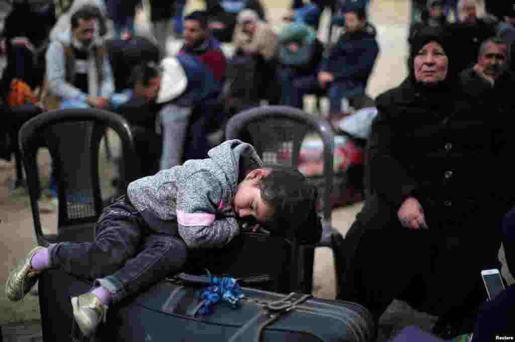 A girl sleeps on a suitcase as she waits with her family for a travel permit to cross into Egypt through the Rafah border crossing after it was opened by Egyptian authorities for humanitarian cases, in the southern Gaza Strip February 8, 2018.