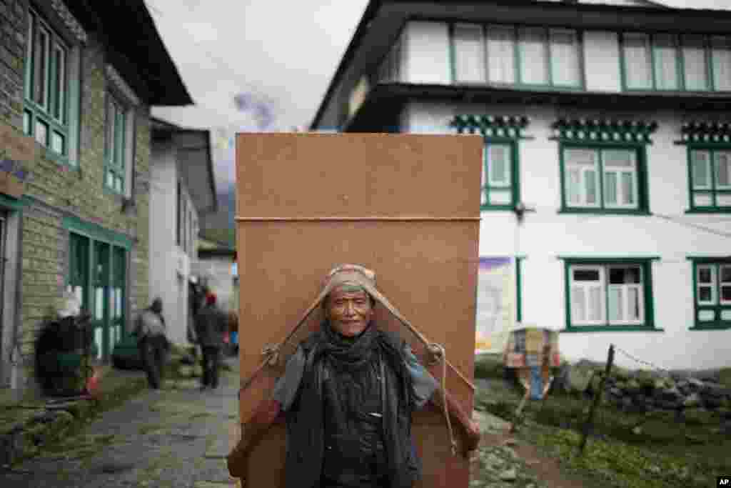 A Nepalese laborer transports a piece of plywood at Lukla, Nepal. 