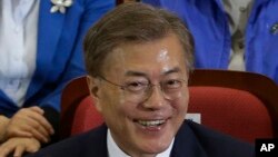 Moon Jae-in of the Democratic Party smiles as and leaders and members of the party watch local broadcast media's results of exit polls in the presidential election in Seoul, South Korea, May 9, 2017.