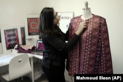 In this Tuesday, January 29, 2019 photo, designer Natalie Tahhan works on a modern version of the traditional Palestinian thobe in her studio in east Jerusalem.